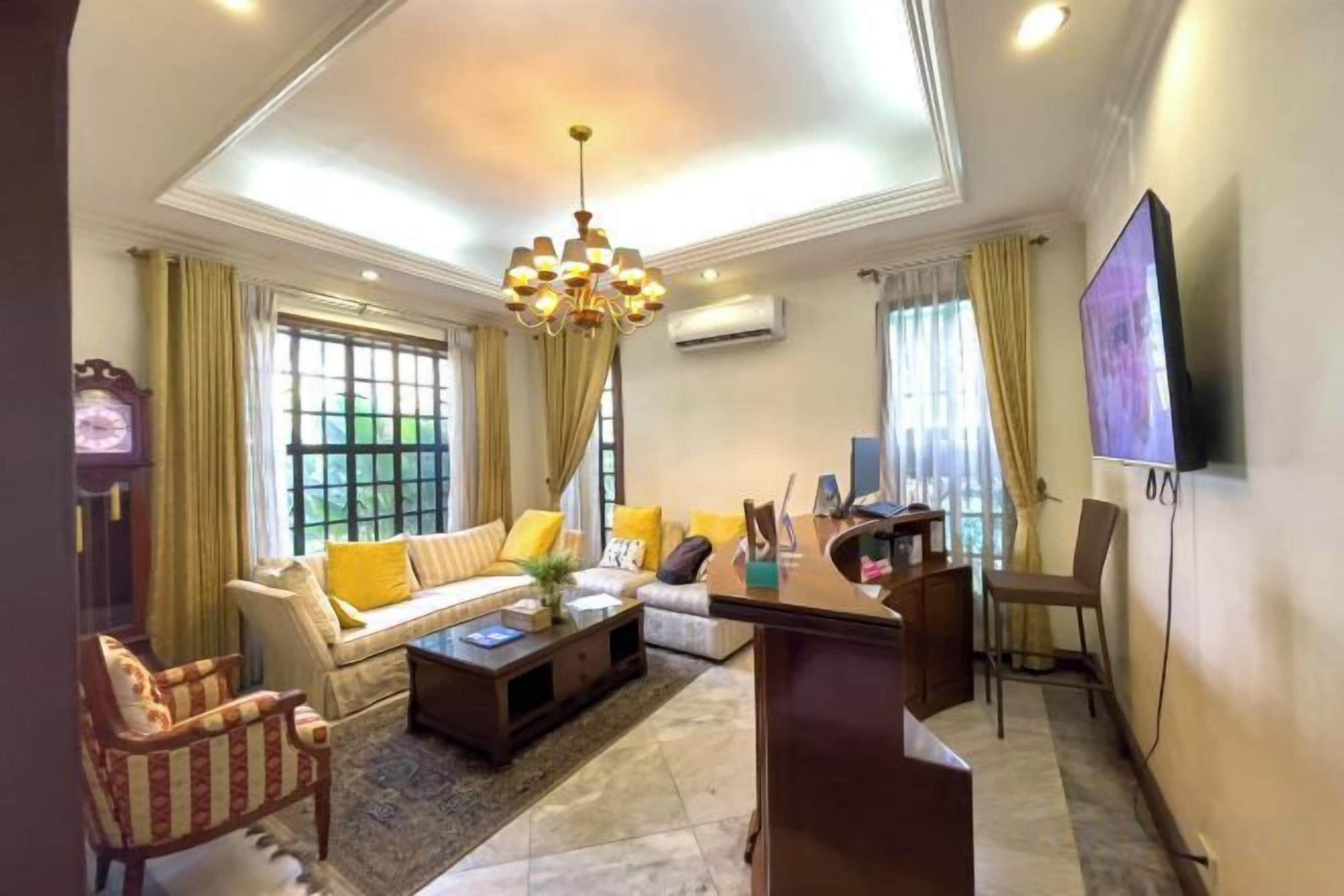 A living room with a sofa, armchairs, a coffee table, and a TV.