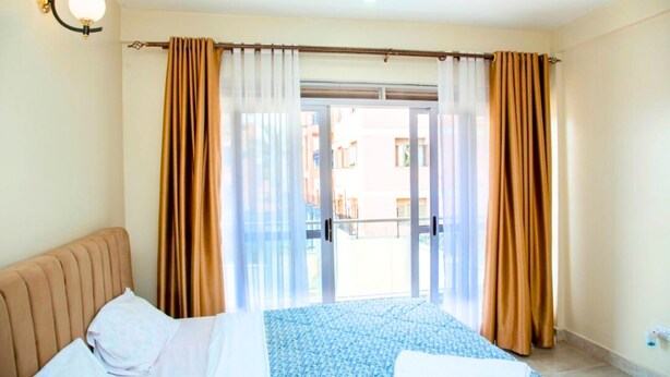 Een hotelkamer met een bed, een raam met gordijnen en uitzicht op het omliggende landschap.
