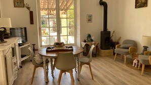 Ein gemütliches Wohnzimmer mit Kamin, einem Esstisch mit Stühlen, einem Fernseher und einem großen Fenster.