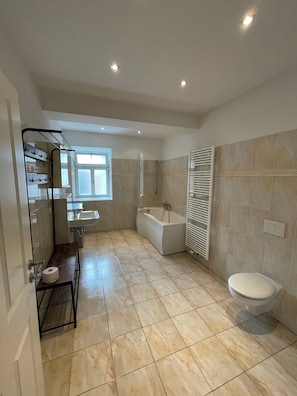 A modern bathroom with a bathtub, toilet, and sink.