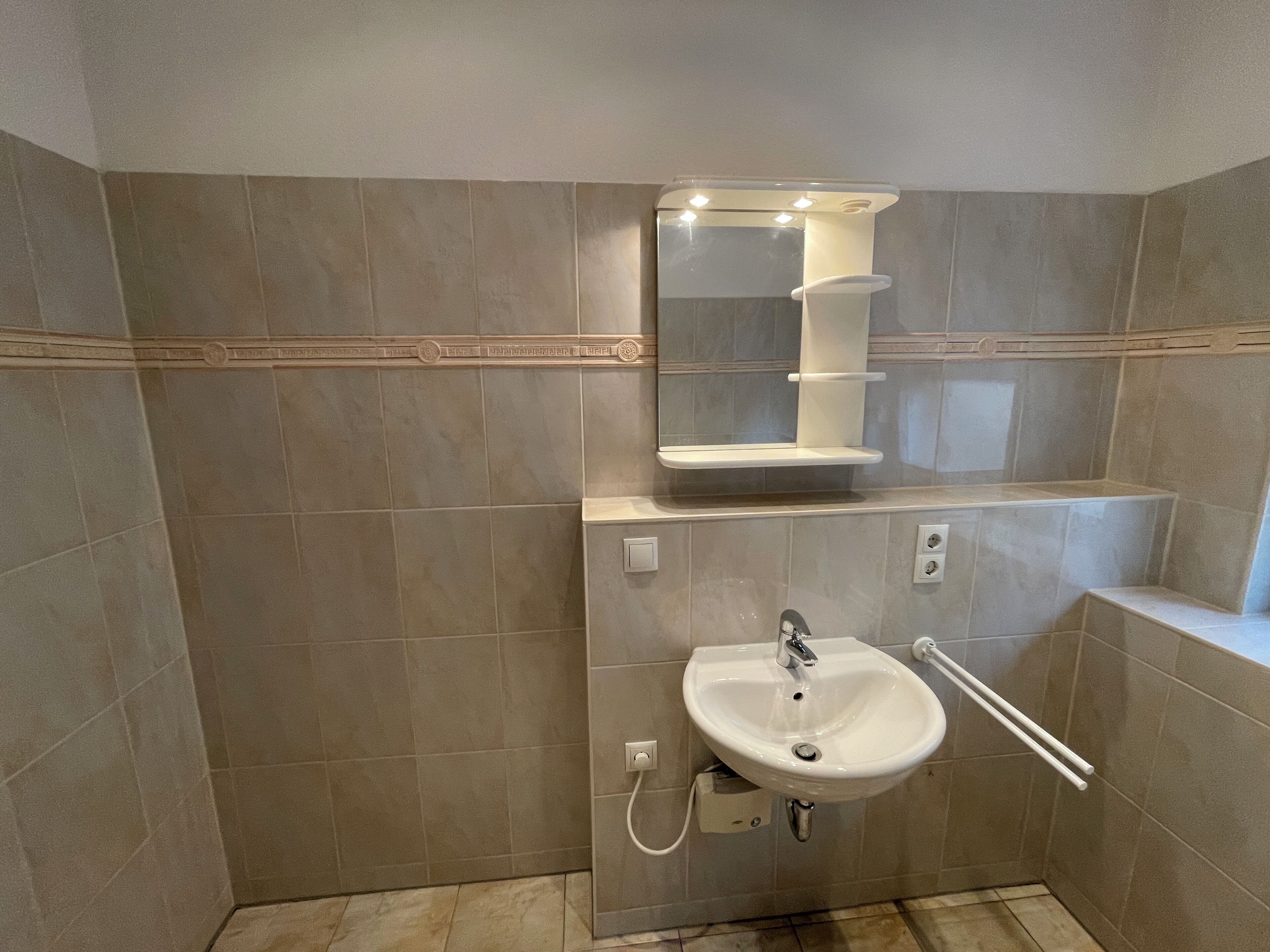 A bathroom with a sink, mirror, and towel rack.