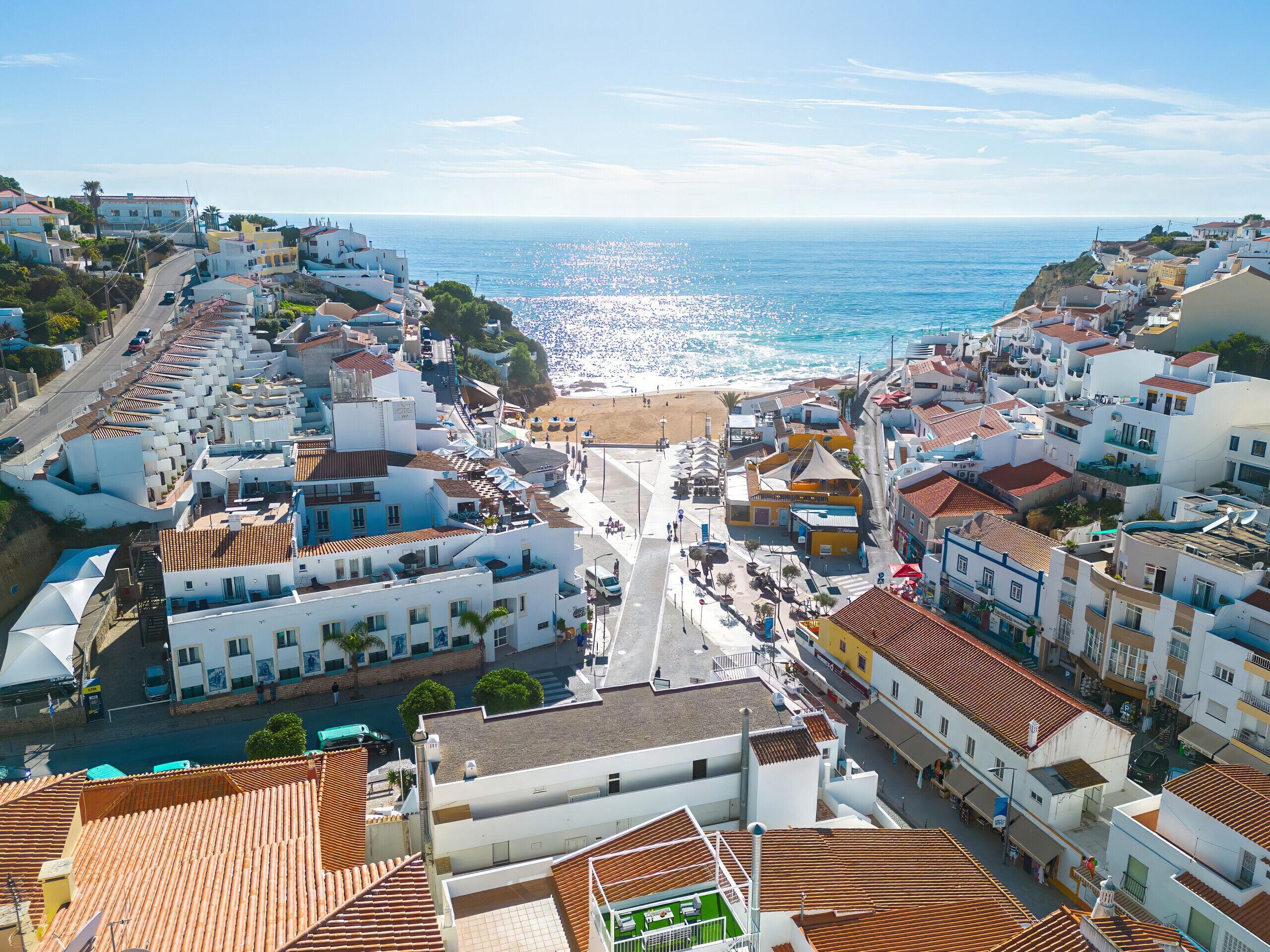 A coastal town with white buildings, a beach, and a clear view of the sea.