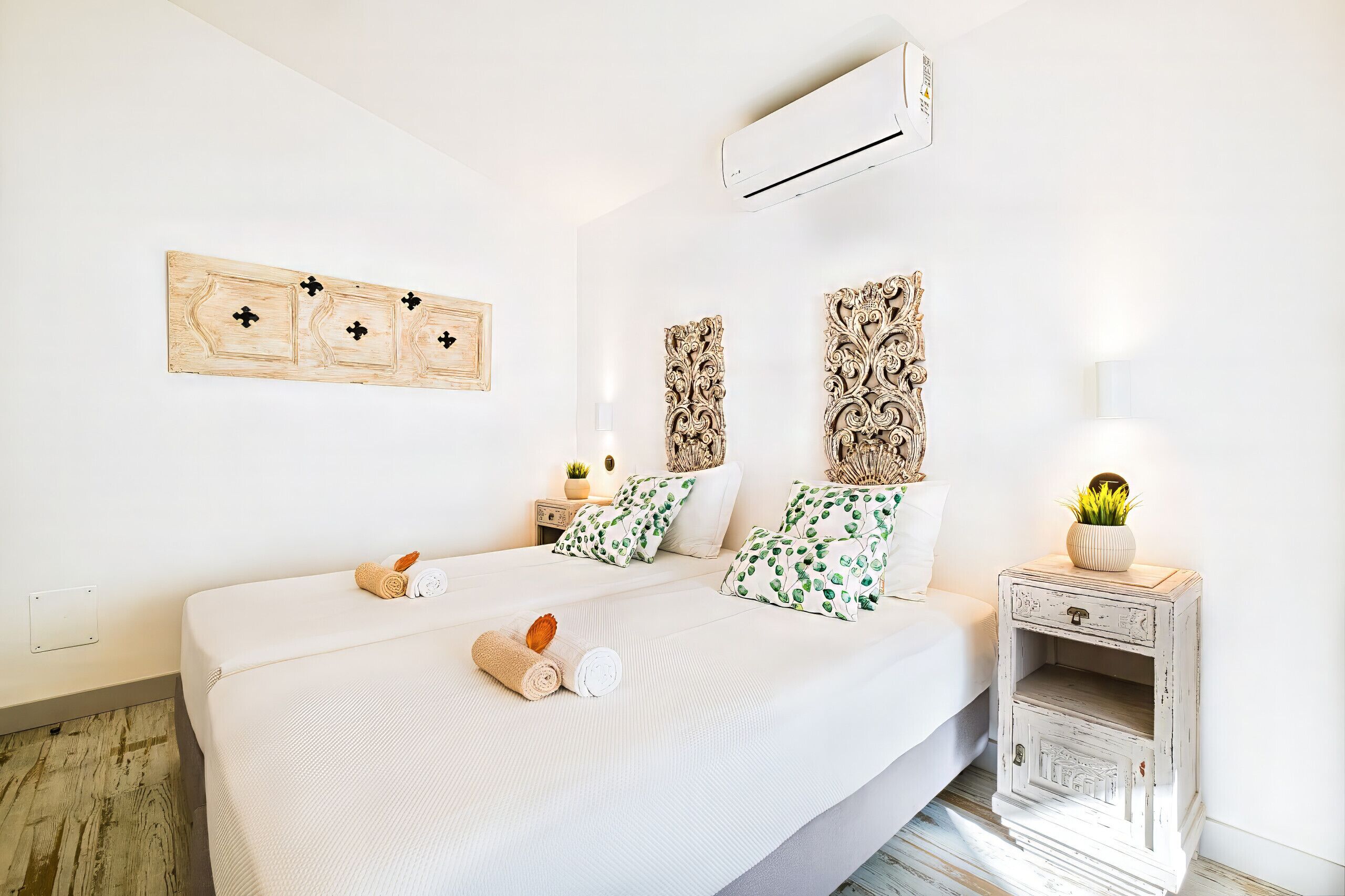 Ein Hotelzimmer mit einem großen Bett, zwei Nachttischen, Wanddekoration und einer Klimaanlage.