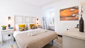 Een moderne slaapkamer met een bed, nachtkastjes, een bureau, een stoel, een spiegel en een schilderij aan de muur.
