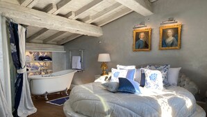 Une chambre à coucher avec un lit rond, une baignoire et deux portraits encadrés accrochés au mur.