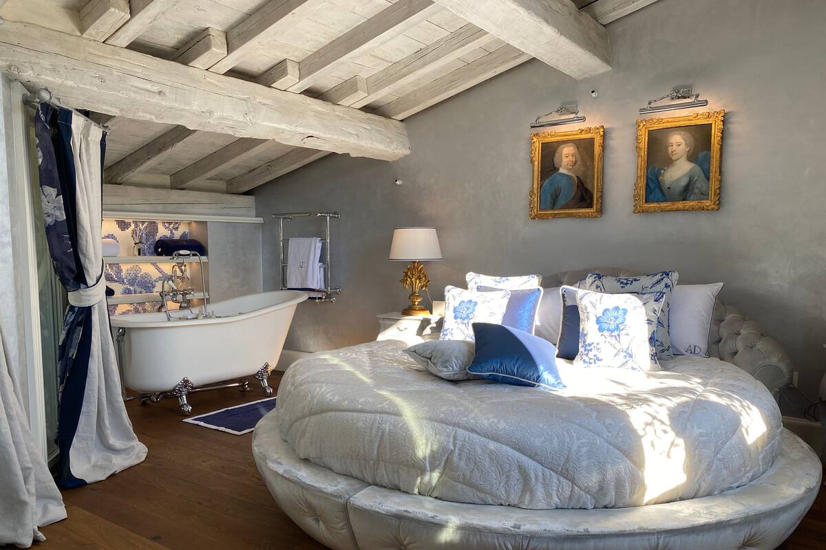 Un dormitorio con cama redonda, bañera y dos retratos enmarcados en la pared.