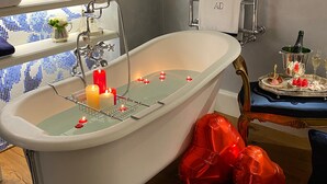 Une salle de bain avec une baignoire sur pieds, un porte-serviettes et une fenêtre donnant sur la ville.