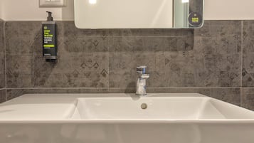 A bathroom with a white sink, a faucet, a soap dispenser, and a mirror.