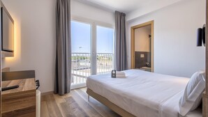 Una habitación de hotel moderna con una cama grande, un escritorio y un balcón con vistas.
