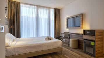 Una habitación de hotel con cama, escritorio, televisor y minibar.