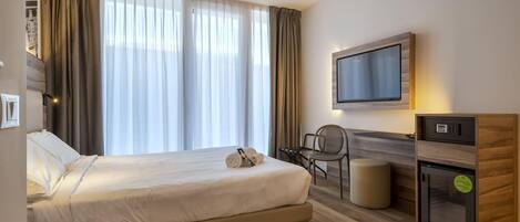 Une chambre d’hôtel équipée d’un lit, d’un bureau, d’une télévision et d’un mini-bar.