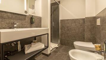 A modern bathroom with a large mirror, a sink, a toilet, and a shower area.