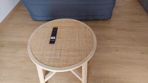Una sala de estar con un sofá, una mesa redonda y un control remoto sobre la mesa.