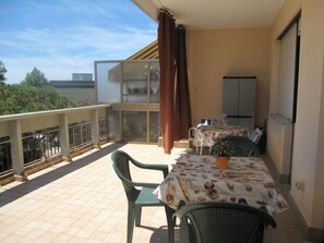 A balcony with a table and chairs, a potted plant, and a view of the city.