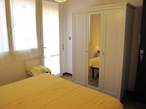 A bedroom with a bed, a chair, a wardrobe, and a mirror.