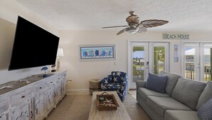 Un soggiorno con televisione, ventilatore a soffitto, divano e tavolino.