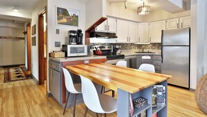 A modern kitchen with white cabinets, a wooden island, and a stainless steel refrigerator. - Mountain Views at Mt Green: 2 BR/2BA, Shuttle, Discounted Ski Rentals, Pool, Hot Tub and More! (Killington)