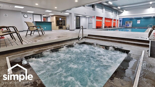An indoor swimming pool with a hot tub, seating area, and a view of the sky through the ceiling. - Mountain Views at Mt Green: 2 BR/2BA, Shuttle, Discounted Ski Rentals, Pool, Hot Tub and More! (Killington)