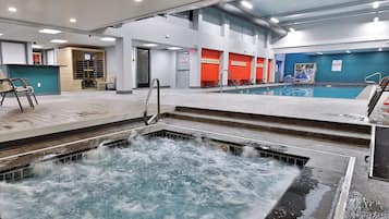 Una piscina interior con un jacuzzi, zona de estar y vistas al cielo a través del techo.
