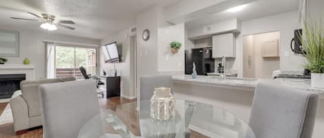 A modern kitchen with a refrigerator, stove, and microwave. There is a dining area with a glass table and chairs.