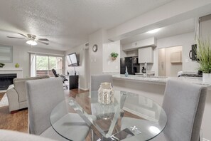 Una cocina moderna con refrigerador, estufa y comedor con mesa de vidrio.