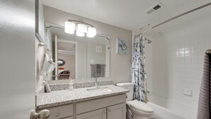 A bathroom with a sink, mirror, toilet, and shower.