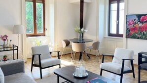 Un salón con una mesa de comedor redonda, cuatro sillas, una mesa baja y una araña.