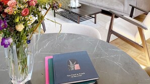 Una sala de estar moderna con un sofá gris, una mesa de centro y un jarrón con flores. En la mesa hay un libro titulado "Van Cleef & Arpels".