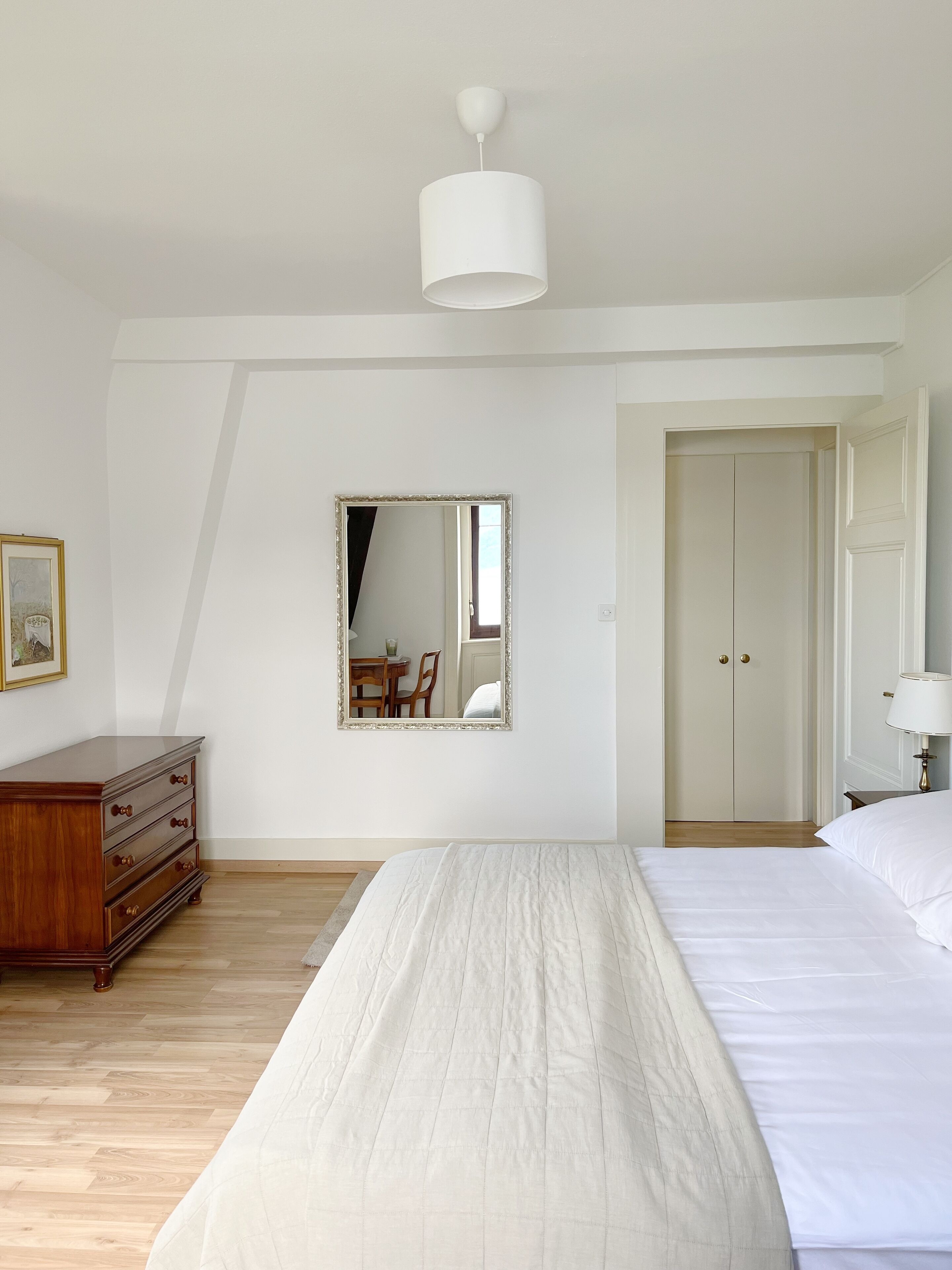 Une chambre à coucher comprenant un lit, une commode, un miroir et une armoire.