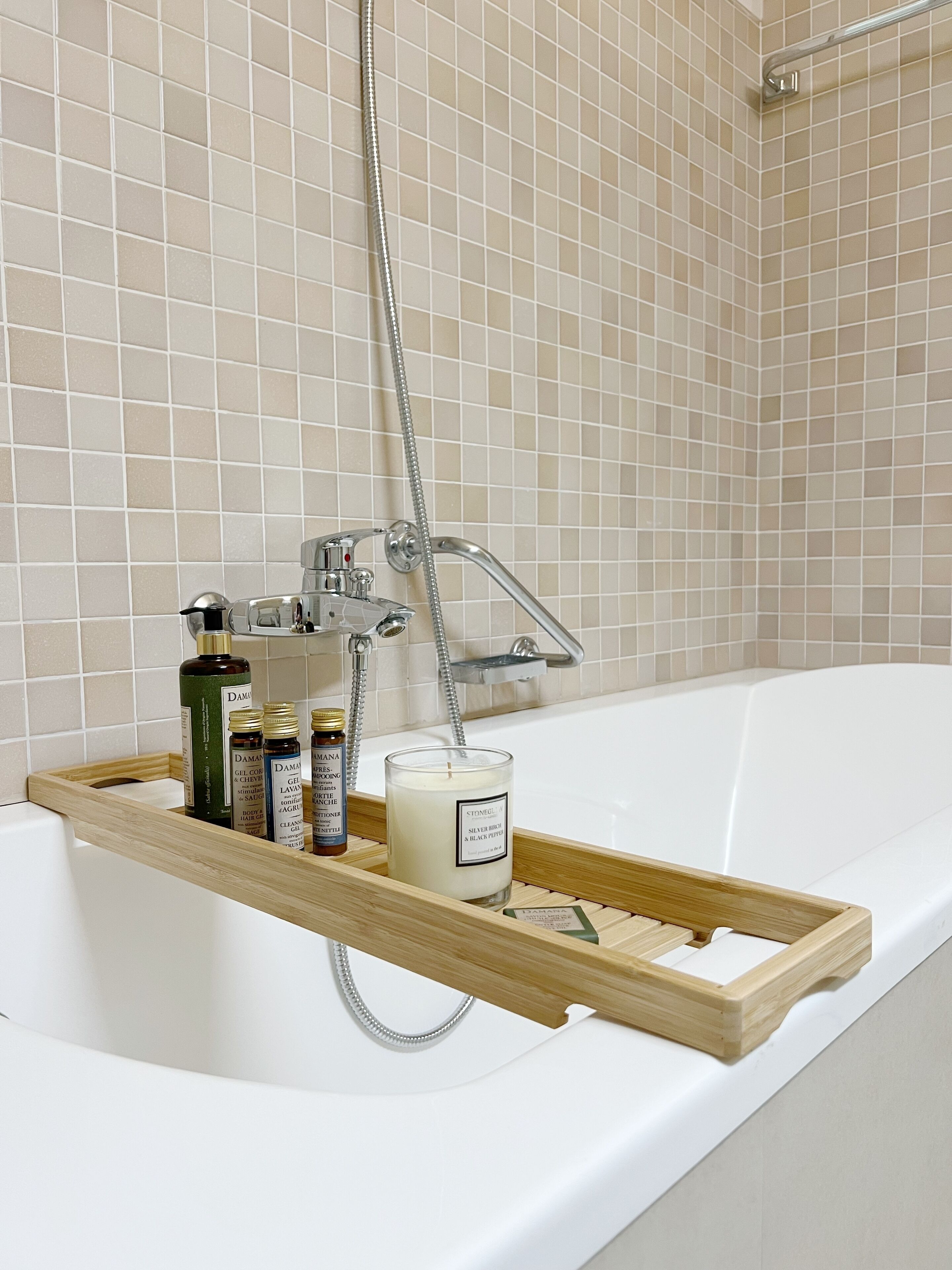 A bathroom with a bathtub, a shower, and a wooden tray holding toiletries.