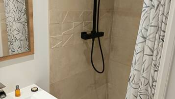 A modern bathroom with a shower, a sink with a mirror, and a wooden vanity.