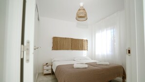 Ein Schlafzimmer mit Bett, Nachttisch und einer gewebten Wandbehange.