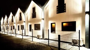 Une rangée de bâtiments blancs, dotés de nombreuses fenêtres, et une clôture en métal à l’avant.