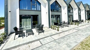 Un hôtel moderne doté de grandes fenêtres, d’un espace extérieur aménagé pour s’asseoir et d’une terrasse propre et bien entretenue.