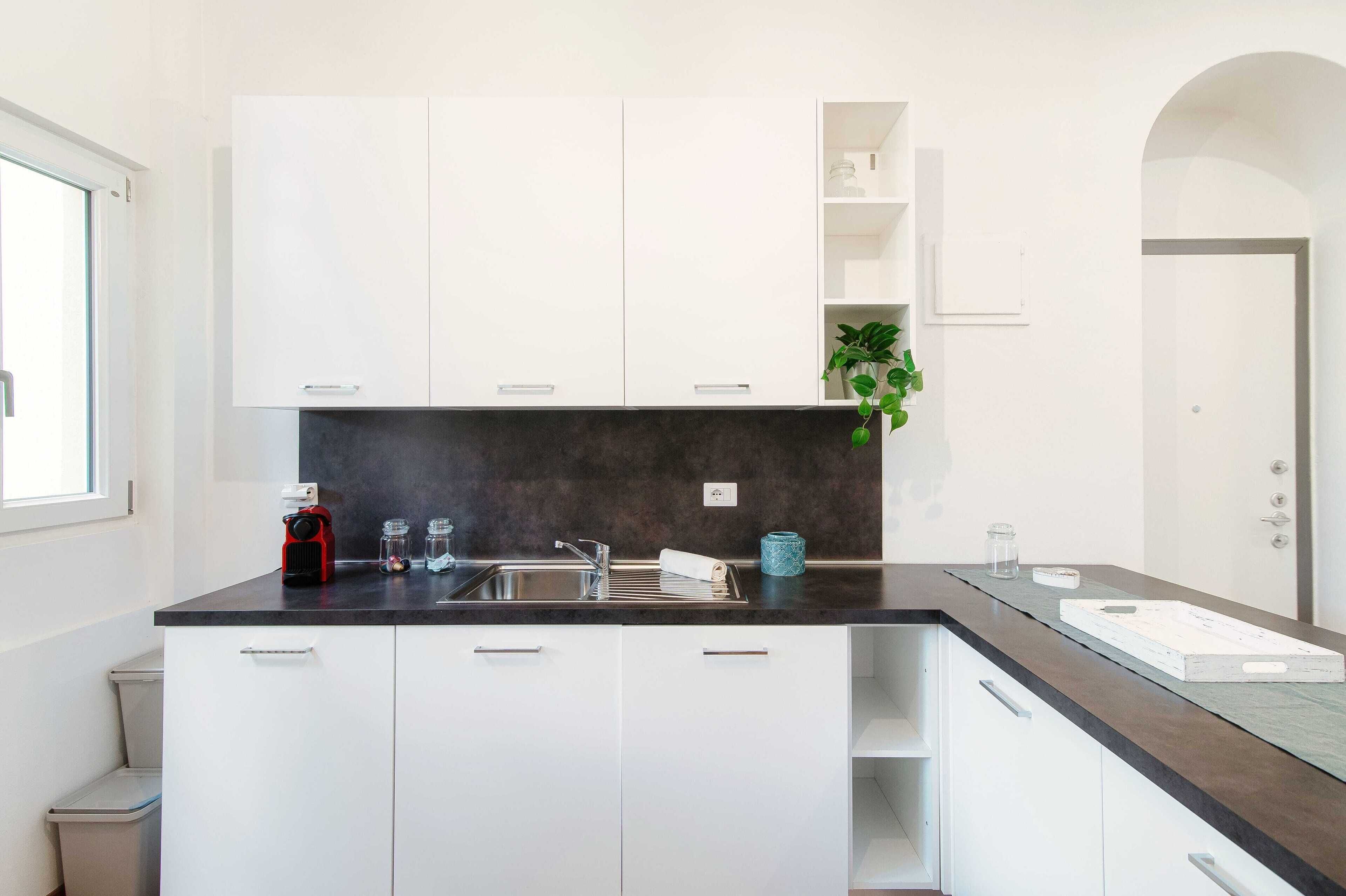 A modern kitchen with white cabinets, a dark countertop, and a built-in oven.