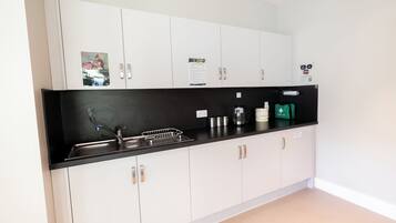 Una cocina moderna con armarios blancos, encimera negra y electrodomésticos de acero inoxidable.