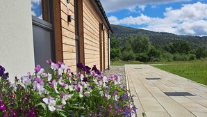 Un bâtiment en bois avec une fenêtre et un jardinier devant.