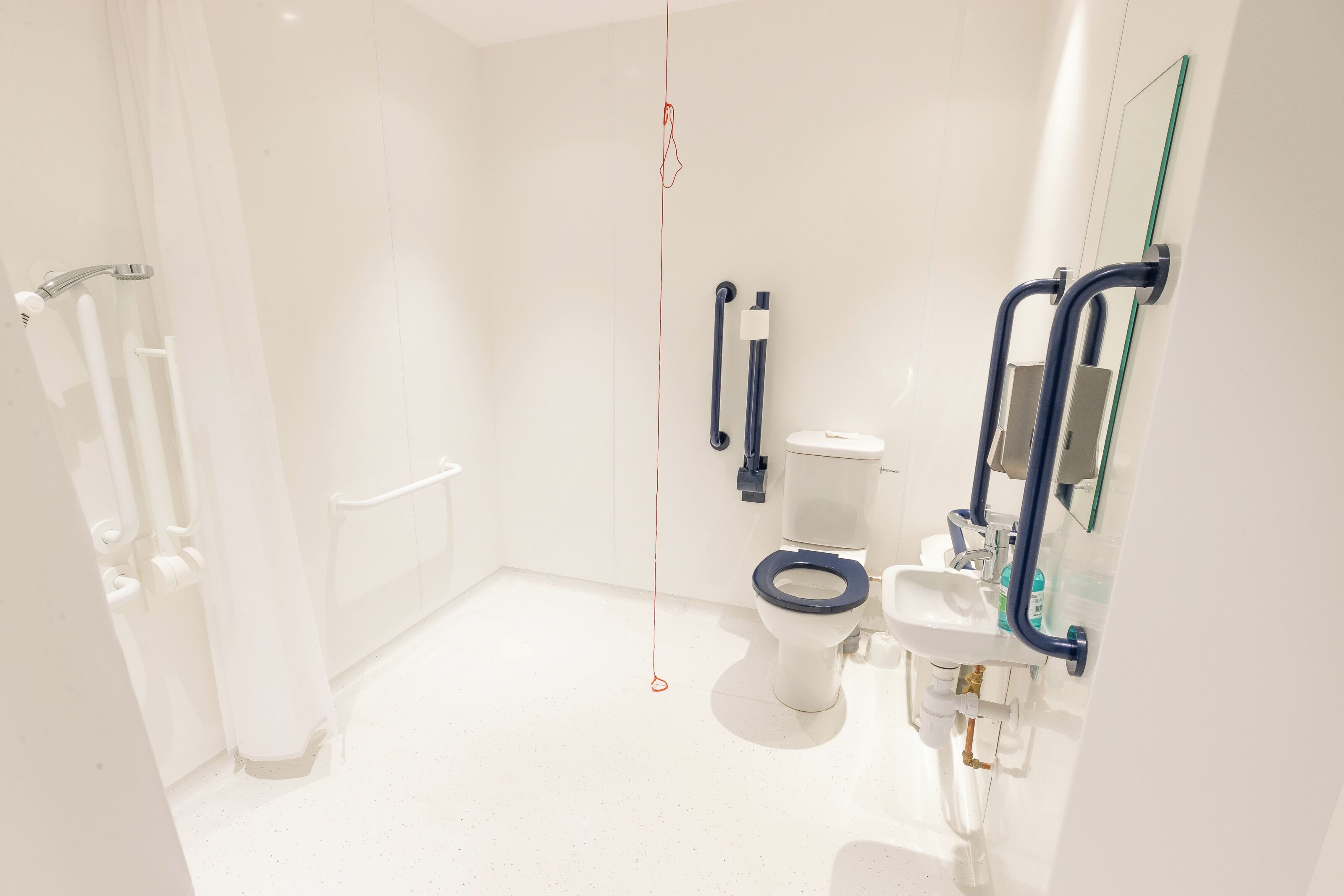 A modern bathroom with a white toilet, a sink, and a glass shower enclosure.