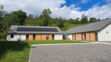 A modern building with a flat roof, solar panels, and a gravel driveway.