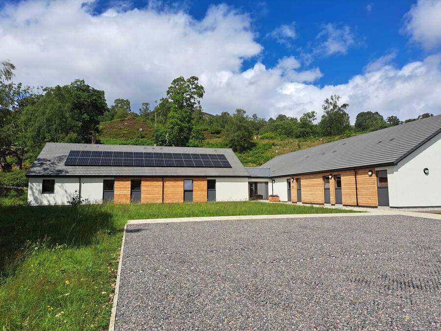 A modern building with a flat roof, solar panels, and a gravel driveway.