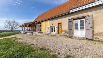 Ein rustikales Haus mit Kiesweg, Holzveranda und einem roten Ziegeldach.