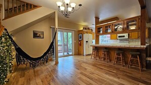 Een ruime keuken met houten kastjes, een centraal eiland met barkrukken, en een kroonluchter.