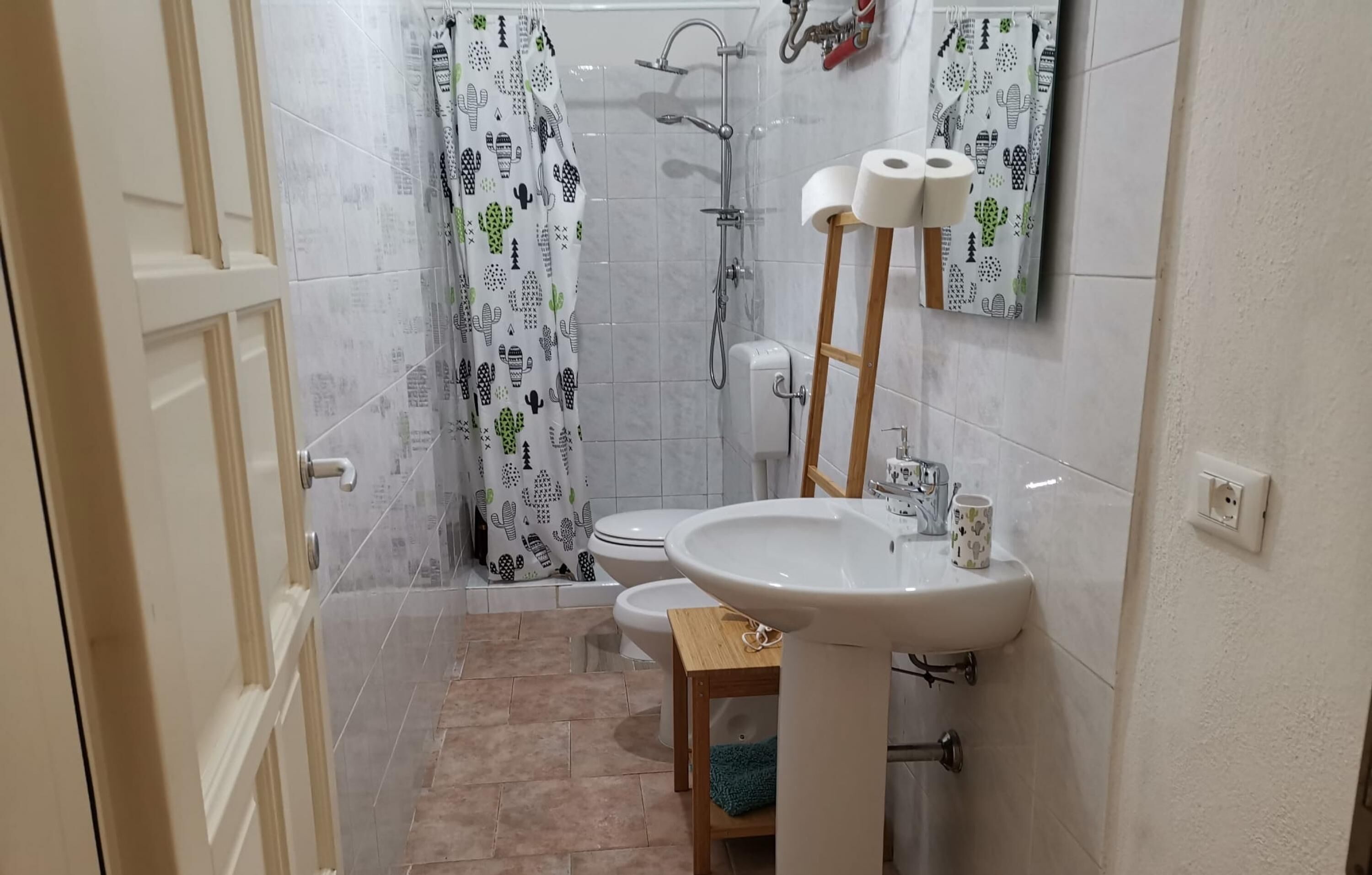 A bathroom with a shower, toilet, sink, and a mirror.