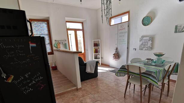 A kitchen with a dining area, a refrigerator with handwritten notes, a window with a view, and a clock on the wall. - Casa Circe in Olbia With 1 Bedrooms and 1 Bathrooms (Olbia)