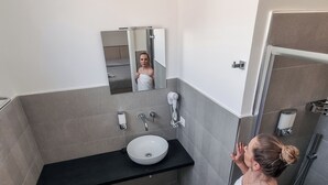 Un bany modern amb un mirall gran, un lavabo, un vàter i una zona de dutxa.