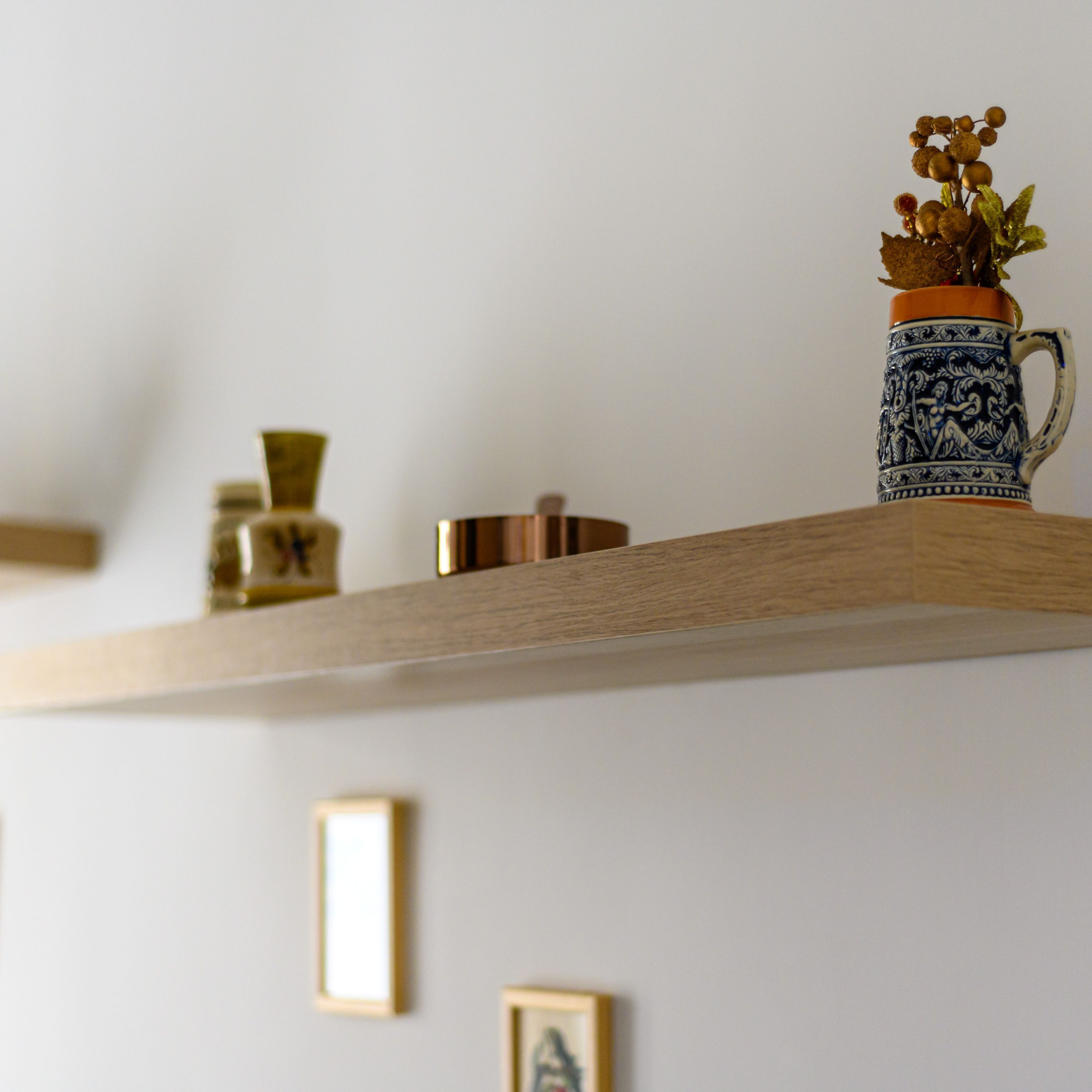 A shelf with decorative items including a blue and white ceramic mug with a handle, a small golden vase, and a wooden box.