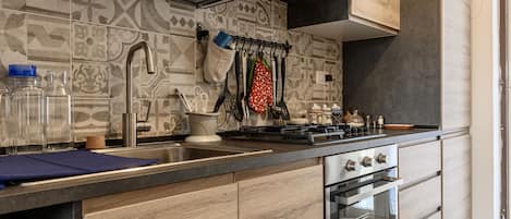 A modern kitchen with wooden cabinets, a stainless steel sink, and a built-in oven.