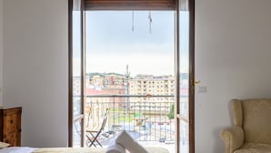 A hotel room with a bed, a chair, and a view of the city through a large window. - Via Coriolano 8 in Naples (Naples)