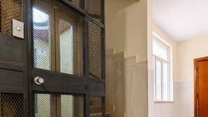 A hallway with a tiled floor, a staircase, and a door with a metal mesh screen. - Via Coriolano 8 in Naples (Naples)