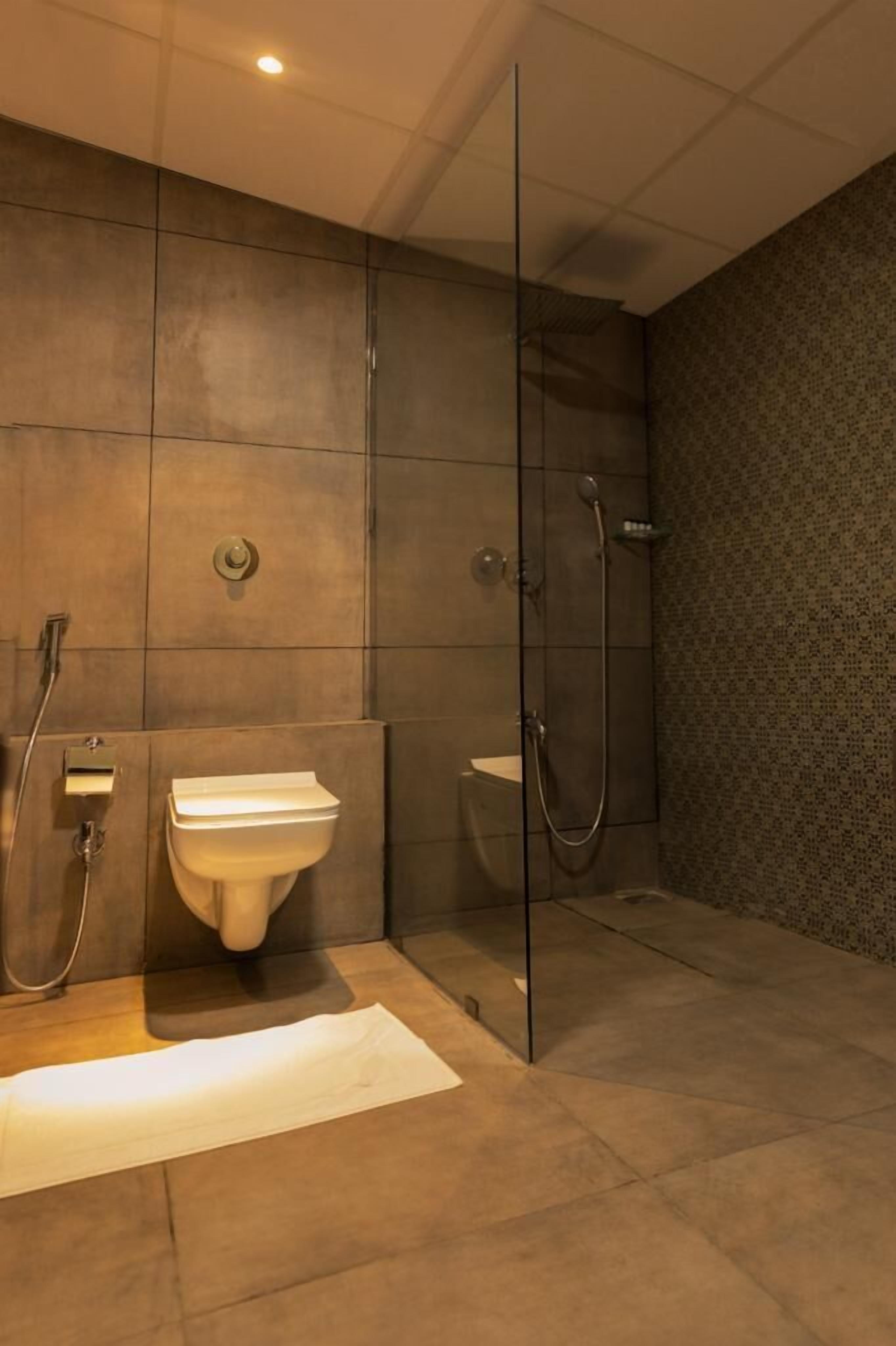 A modern bathroom with a glass shower enclosure, a pedestal sink, and a toilet.